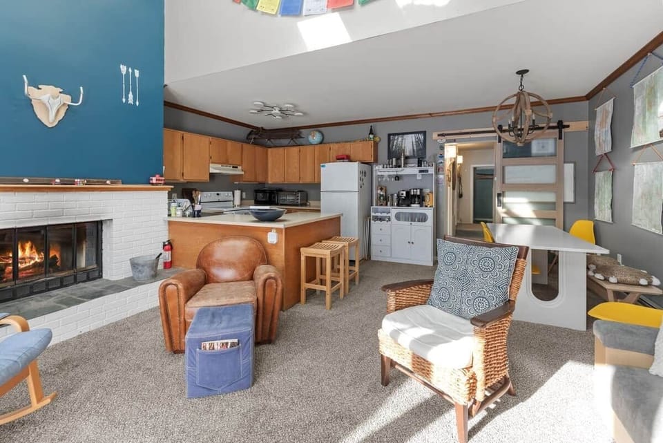 Sun-soaked seating surrounds a charming fireplace, perfect for après-ski evenings! Stay in the action while preparing meals in the open concept kitchen.