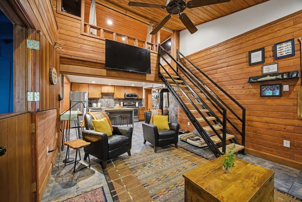 Main living room — wood walls, leather chairs, and the loft above