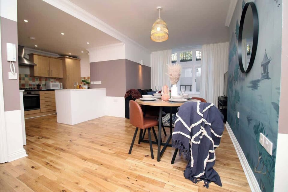 A beautifully styled dining area set within a bright, open-plan space. Featuring elegant décor, feature wall and modern furnishings, it offers a warm, sophisticated setting perfect for relaxed breakfasts, evening meals and social dining.