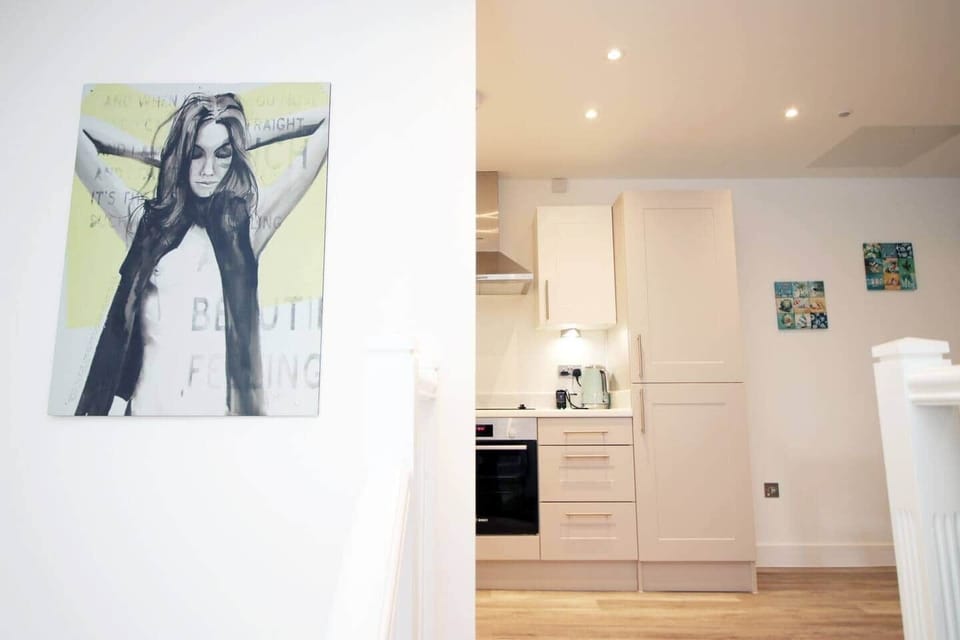 A welcoming view into the modern kitchen, featuring clean white cabinetry, warm wood flooring, 