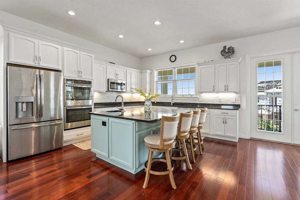 Fully equipped kitchen with stainless steel appliances, white cabinetry, and plenty of space for cooking and gathering