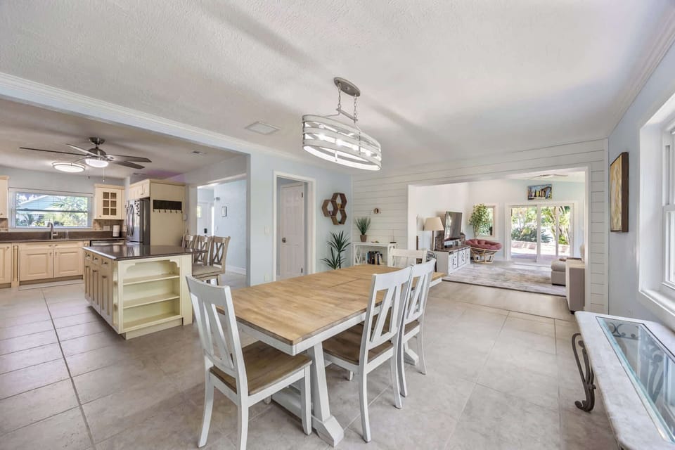 Open dining area with a wooden table and modern lighting adjacent to the kitchen and living room.