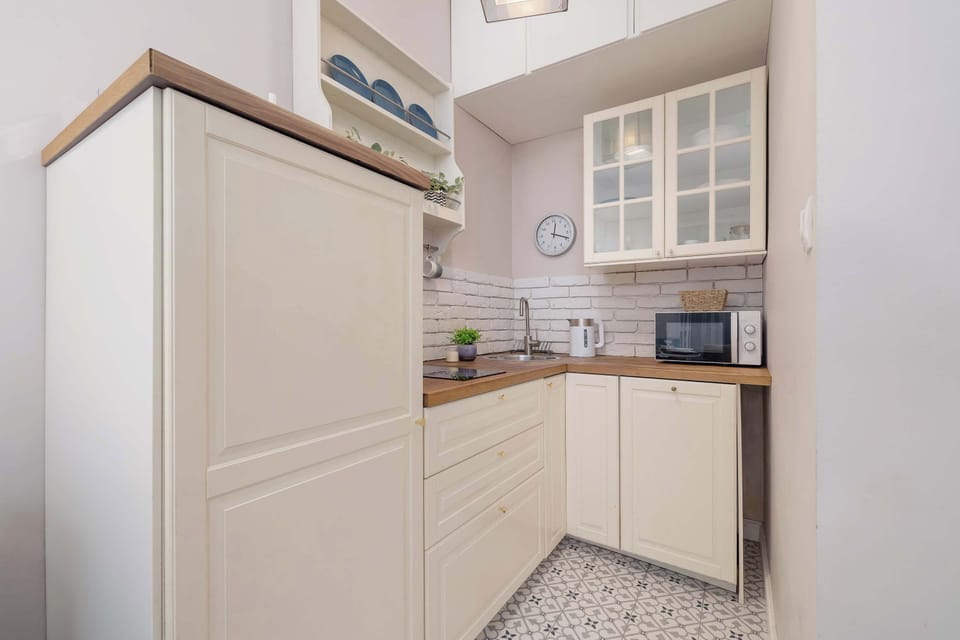 A bright kitchen with white cabinetry, a stove, and modern equipment. The tiled backsplash adds a classic touch.