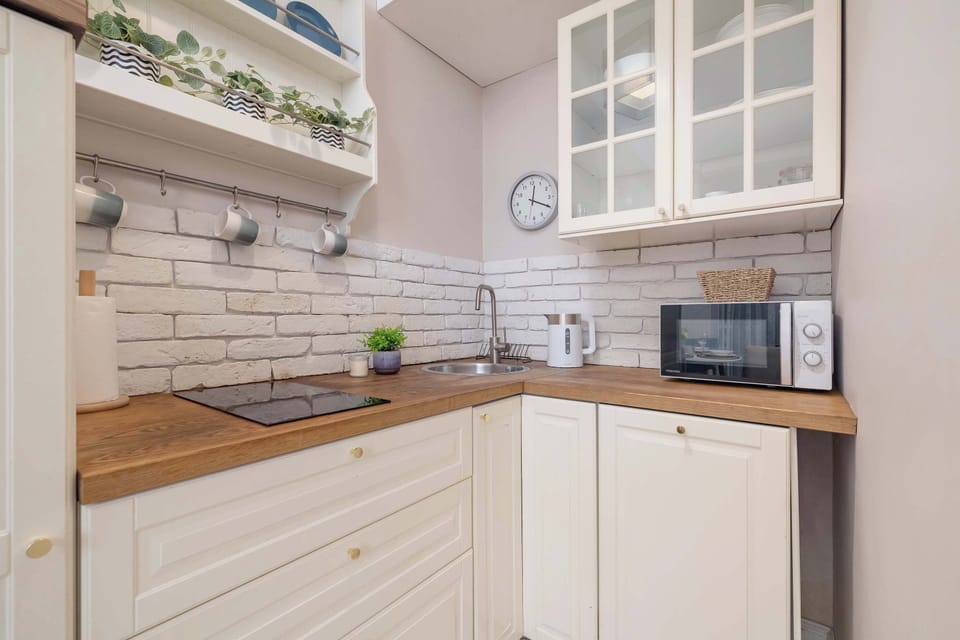 A bright kitchen space with white cabinets and modern appliances. The open shelving and wooden countertop provide a stylish look.