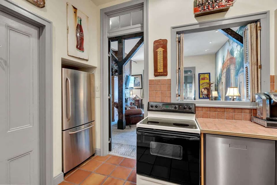 The fully equipped kitchen features modern appliances, warm tile countertops, and charming vintage décor. A pass-through window opens to the living area, keeping the space open and connected while you cook or gather with friends.