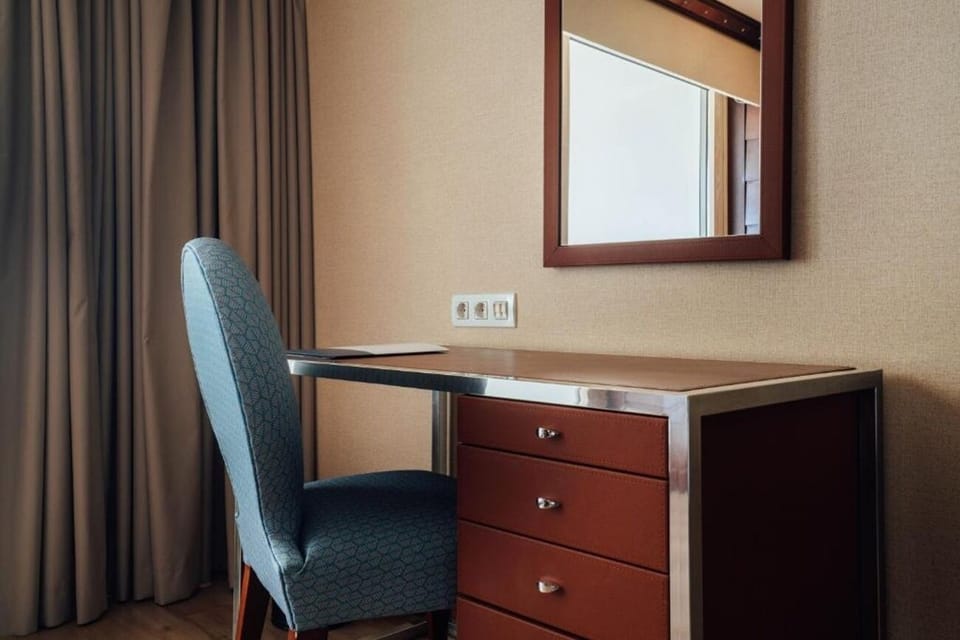 Catch up on emails at a quiet desk by soft drapes.