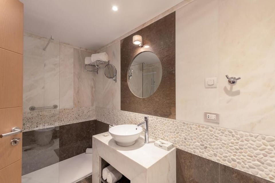 Refresh in a sleek marble bath with walk-in shower.