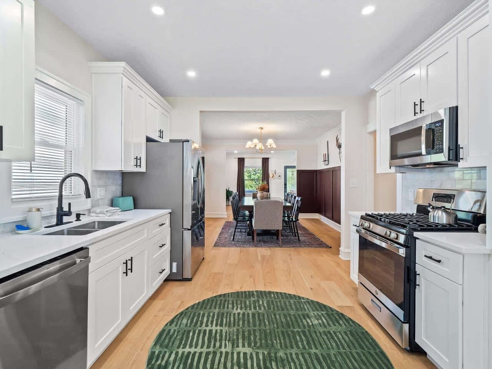 Open kitchen w/ bright white cabinets, long counters, & modern appliances for easy cooking.