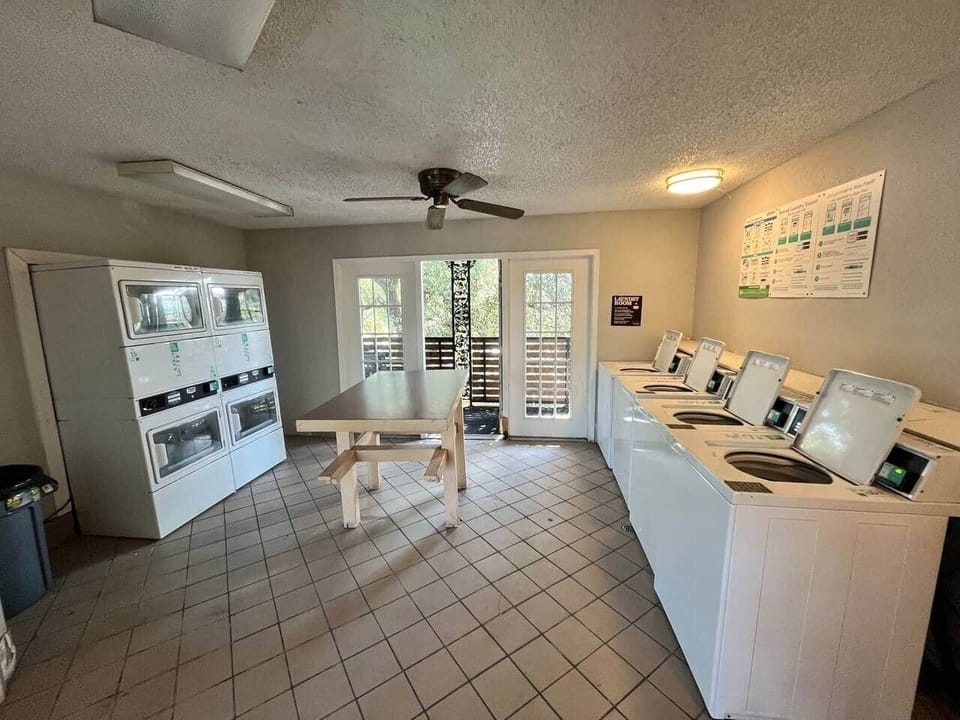 On-site laundry room with multiple washers, dryers, and folding space
