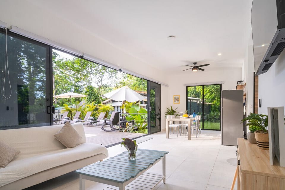 Bright open-concept living area with seamless indoor-outdoor design overlooking the pool at Somnara Flor Silvestre, Playa Chiquita, Costa Rica