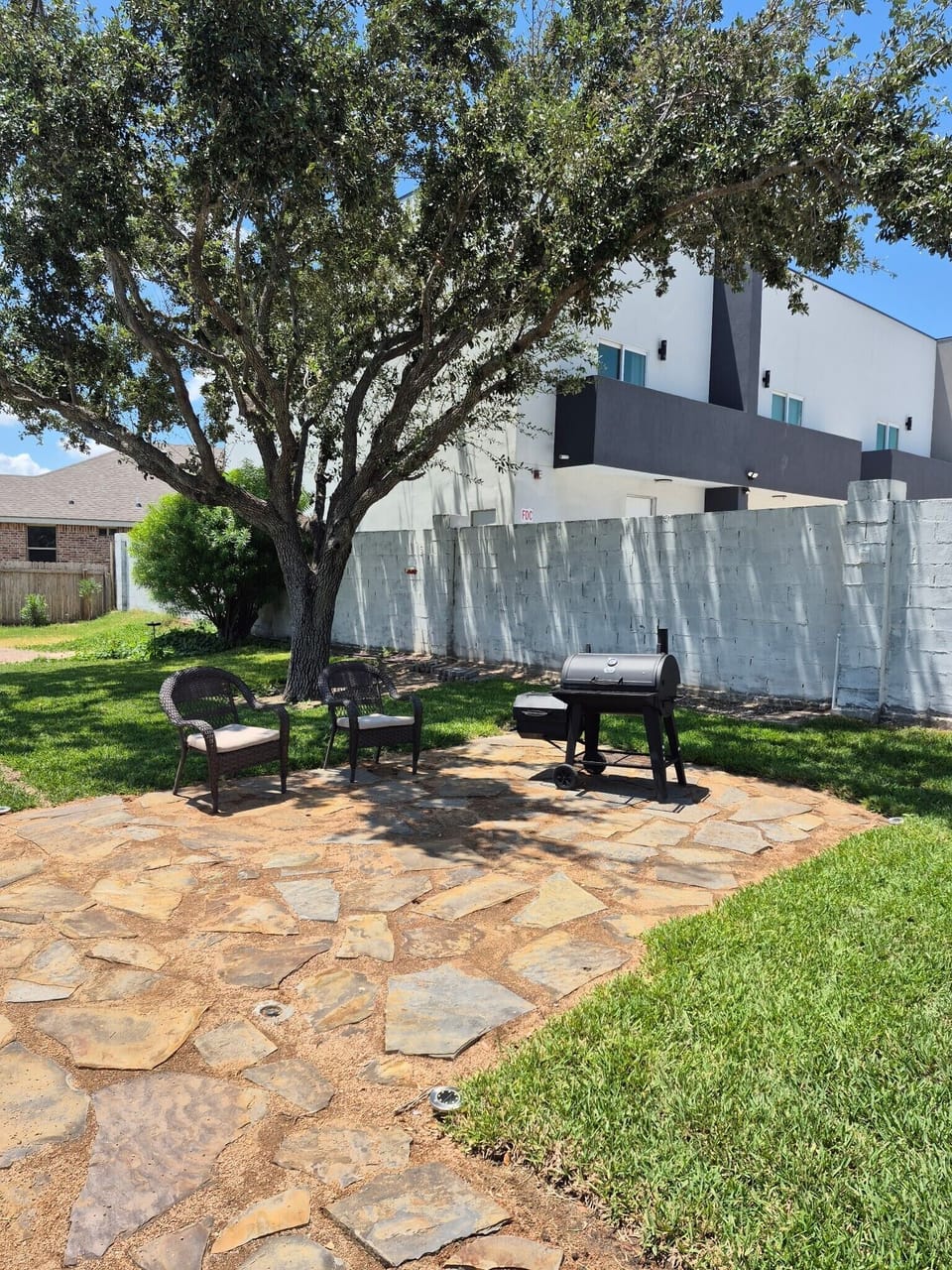 BBQ grill and seating under the shade of trees next to the pool.