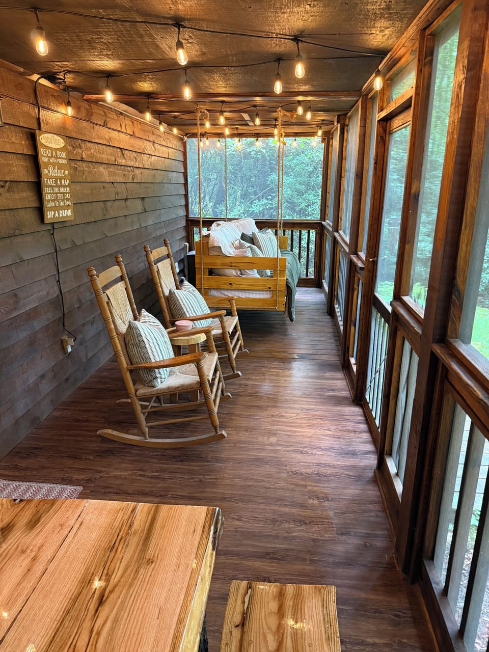 Screened porch offers a table, rockers, and a cozy swing bed.