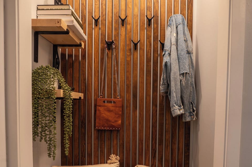 Stylish mudroom with hooks, shelves, and wood detail wall.