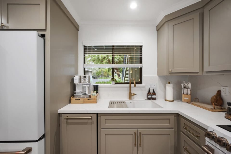 Start your morning right with a fully stocked coffee and tea station in a beautifully designed kitchen featuring brass finishes, sharp cutlery, and all the essentials for home cooking.