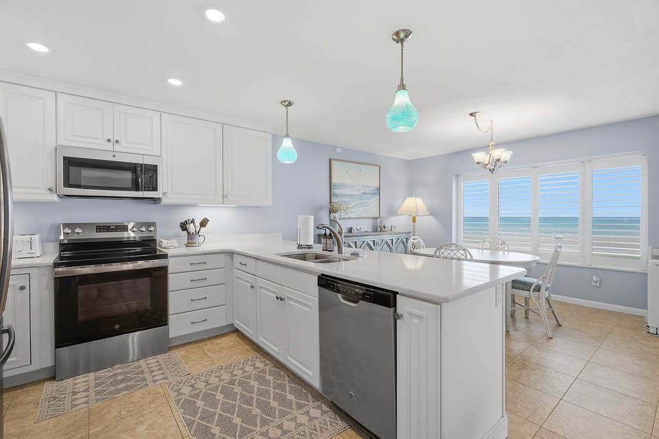 Prepare meals in this bright, fully equipped kitchen featuring modern appliances, spacious countertops, and an open layout. The adjacent dining area offers beautiful ocean views, making every meal part of your relaxing beach stay.