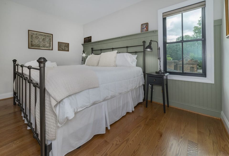 Second bedroom featuring a comfortable king-size bed, en suite bathroom, closet for clothing storage cabinet, and natural light from multiple windows with pulldown shades for comfort and privacy.