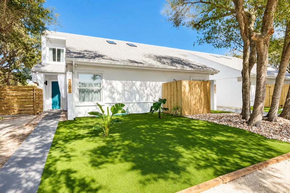 Bright modern exterior with lush turf yard and inviting teal entry