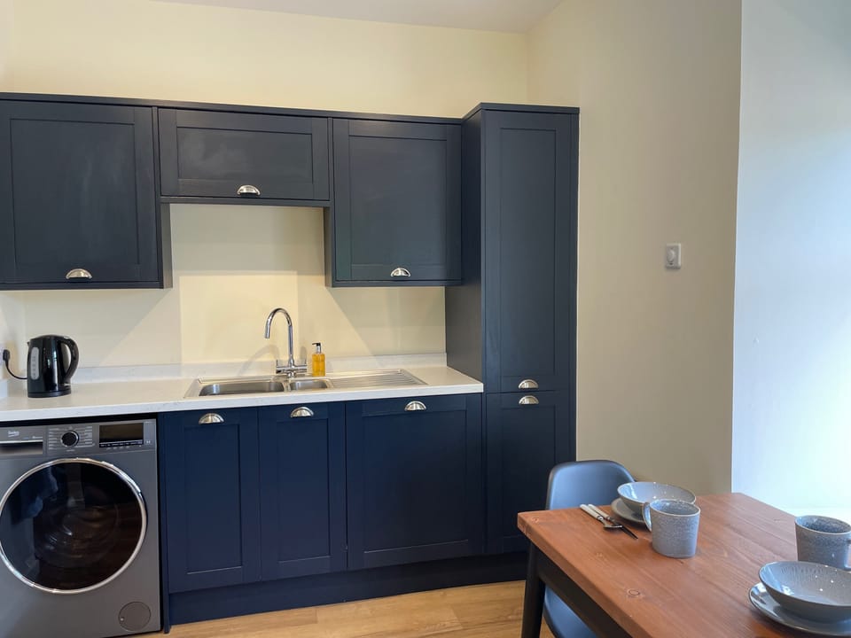 The utility area of the kitchen has washing machine, dishwasher and storage