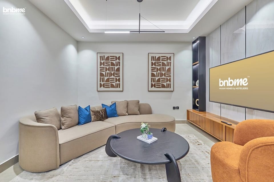 A spacious living room featuring plush seating, a smart TV, and elegant decor, perfect for relaxing or entertaining.