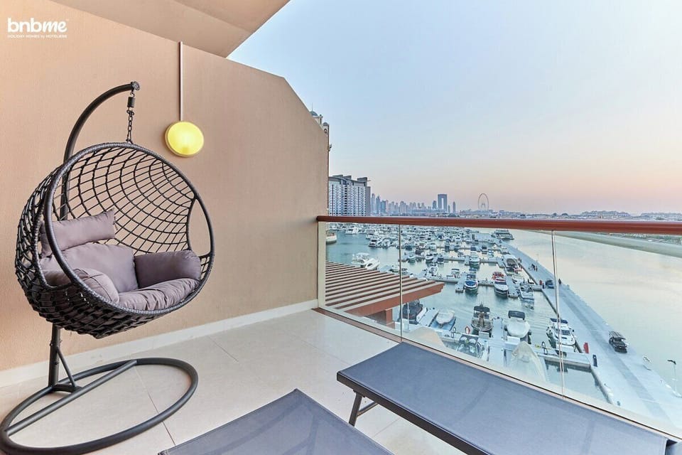 Unwind on the private balcony featuring a sun lounger, single-seater hammock, and breathtaking views of the sea and Ain Dubai.