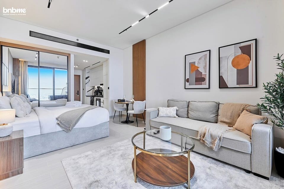 Unwind in the bright and stylish living area featuring a plush sofa bed, modern artwork, soft textiles, and floor-to-ceiling windows that open to a private balcony. Perfect for lounging, reading, or enjoying canal and city views.