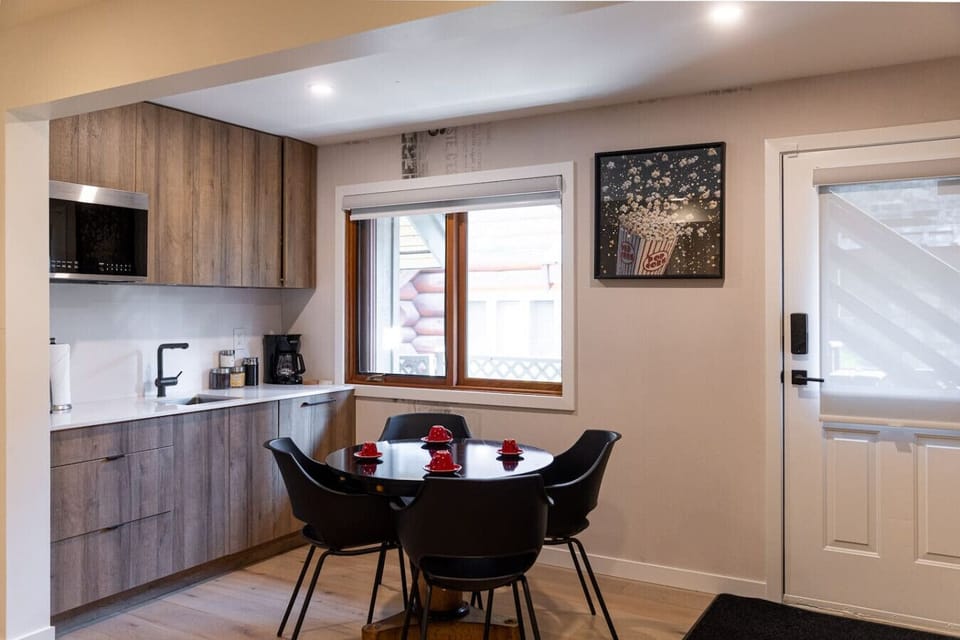 Bright and tidy dining area with modern black chairs, a cozy entryway bench, and a wall-mounted coat rack.