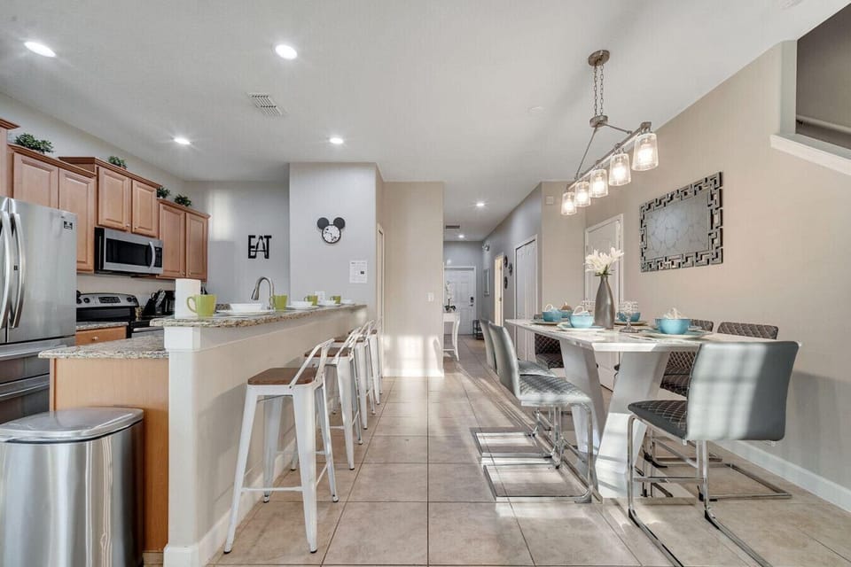 Spacious kitchen and dining area with modern appliances, breakfast bar seating, and a stylish dining table—perfect for shared meals and gatherings.
