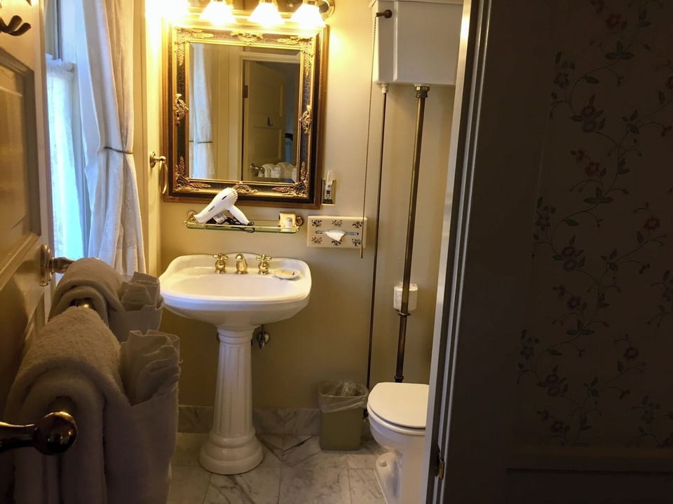 Freshen up easily with classic pedestal sink and warm lighting.