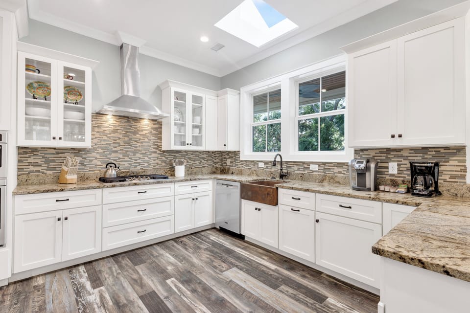 This spacious kitchen features stainless steel appliances, a gas stovetop, elegant copper farmhouse sink, granite countertop space, and a beverage fridge!
