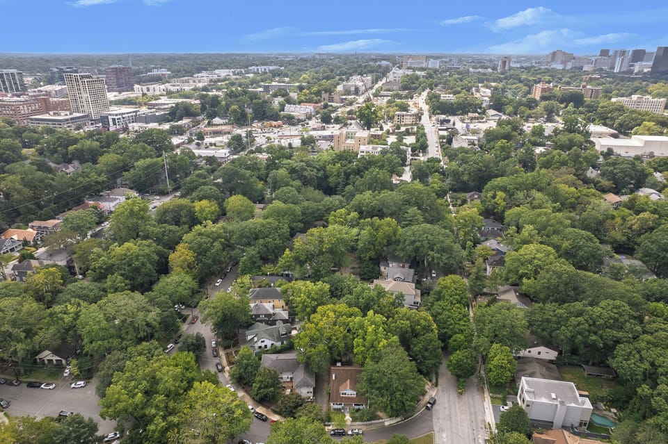 Wide overhead view of the neighborhood with city skyline beyond