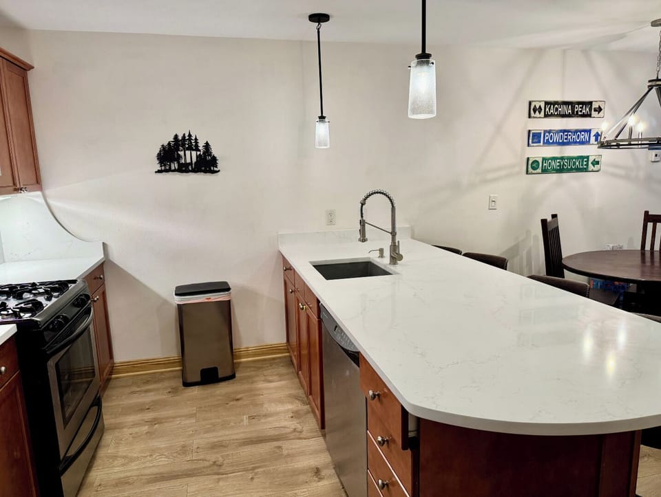 Your fully equipped kitchen features sleek white countertops, modern appliances, and a spacious island—perfect for preparing home-cooked meals and gathering with loved ones during your mountain getaway.