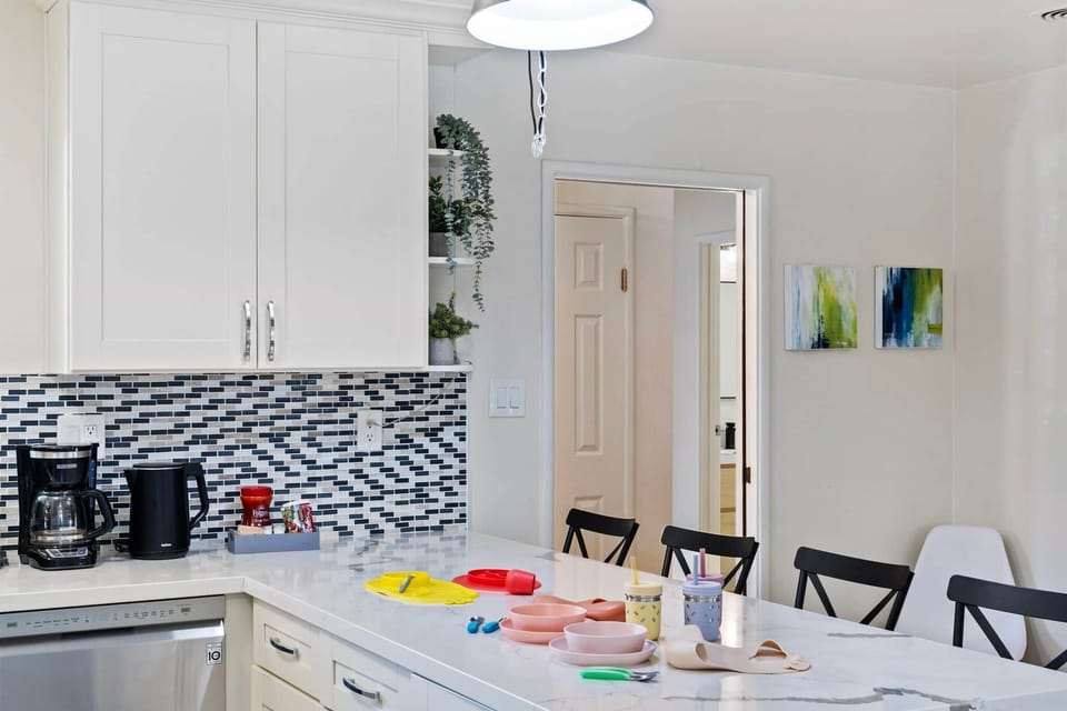 Kitchen counter with coffee maker, kettle, and colorful kids' dishes.