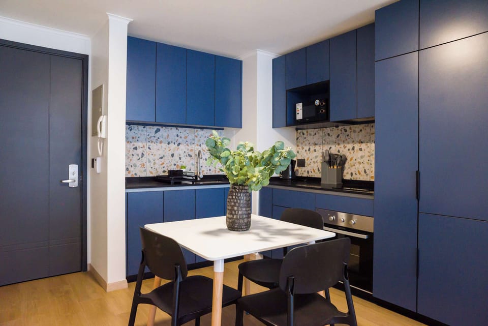 Savor meals in this chic kitchen with stylish blue cabinets and a cozy dining setup, perfect for intimate gatherings.