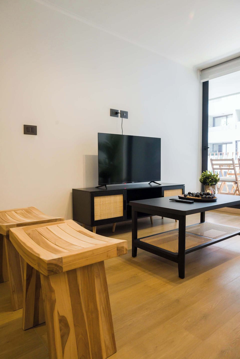 Unwind in this chic living space with a sleek TV setup and ample natural light, perfect for relaxation.