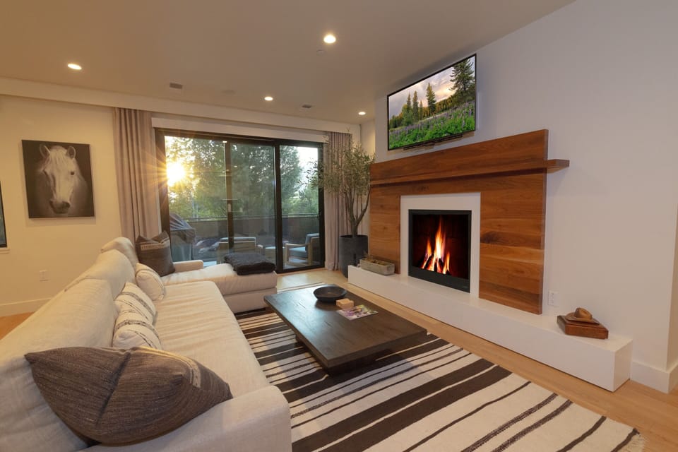 Unwind in your elegant living room where the warmth of the modern fireplace creates the perfect ambiance for cozy evenings, while floor-to-ceiling windows frame your private outdoor space.