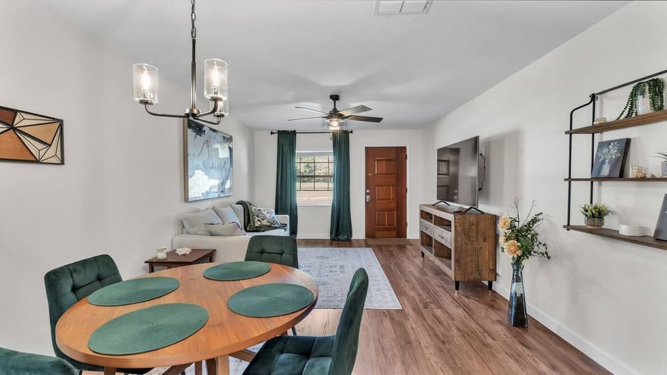 Relax in a cozy living room with plush seating, soft lighting, and warm decor. Connected to a quaint dining area, it features a large TV, perfect for movie nights, unwinding, and conversations with loved ones.