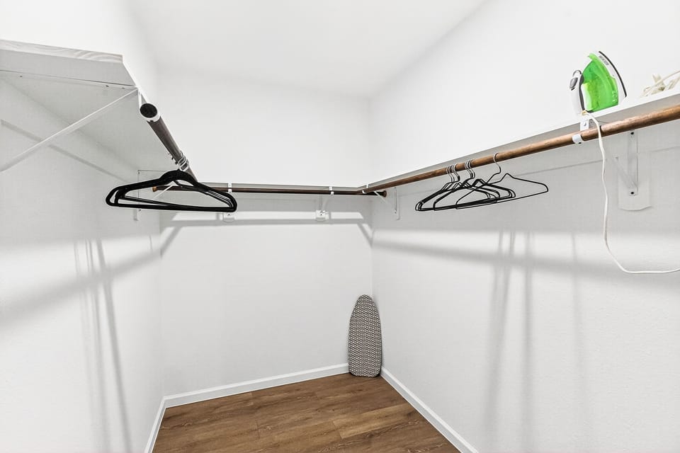 Full walk-in closet with hangers, iron and iron boards.