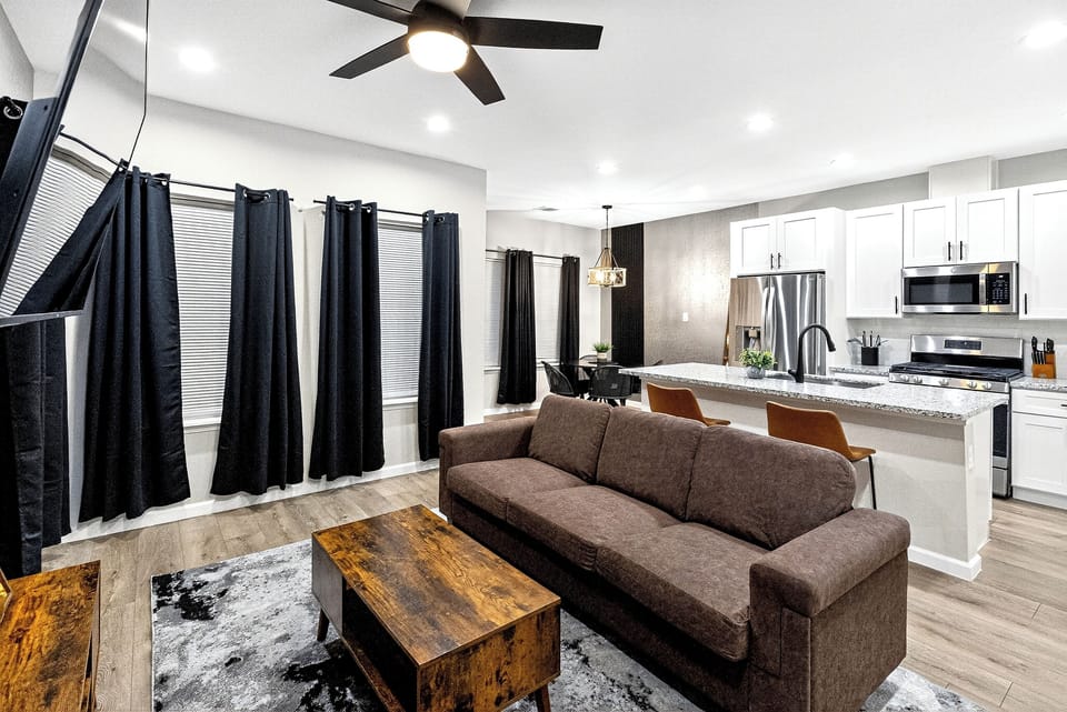 Step into this stylish and cozy living room, featuring a comfortable sofa and armchair set. The room is accented with a 65-inch TV and a black, grey and brown color theme, creating a chic and modern look. Perfect spot for relaxing and winding down.
