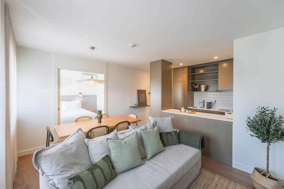 Spacious living room with comfortable sofa, modern décor, and access to the balcony. Ideal for relaxing in Porto, next to the Bom Sucesso Market.