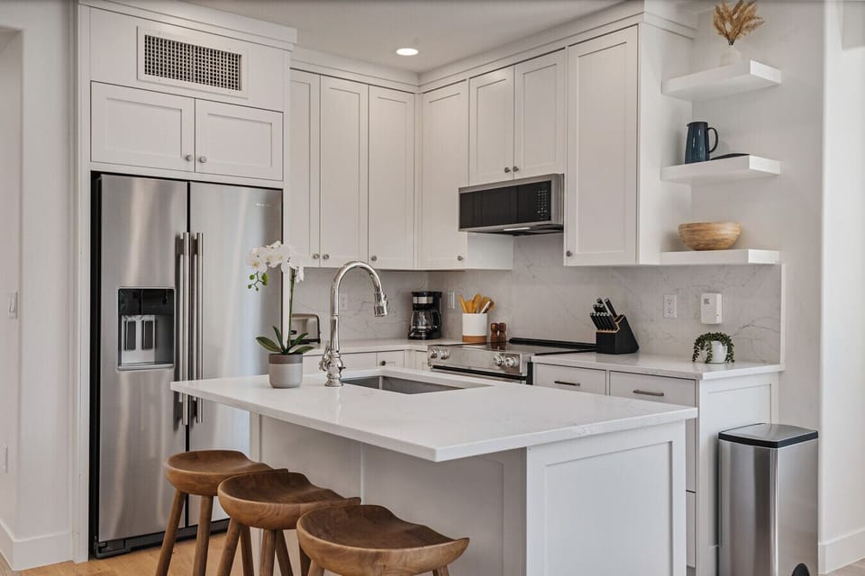 Stocked kitchen with stainless steel appliances, quartzite counters and breakfast bar seating for 3