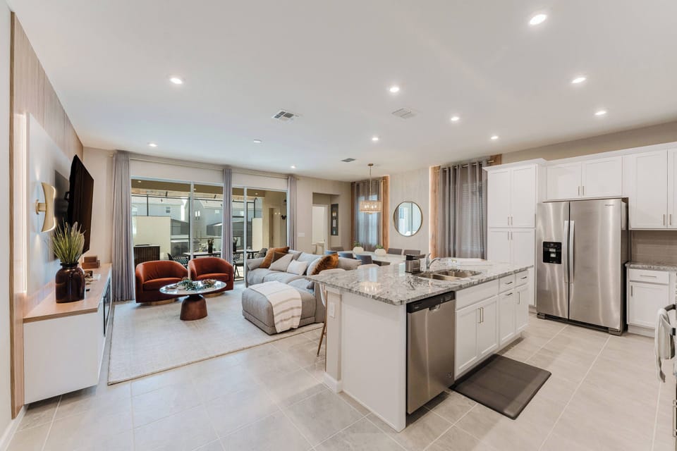Enjoy a bright open-concept living area featuring sleek stainless-steel appliances and a stylish kitchen island, ideal for gatherings. Cozy seating invites relaxation, while large windows bathe the space in natural light.