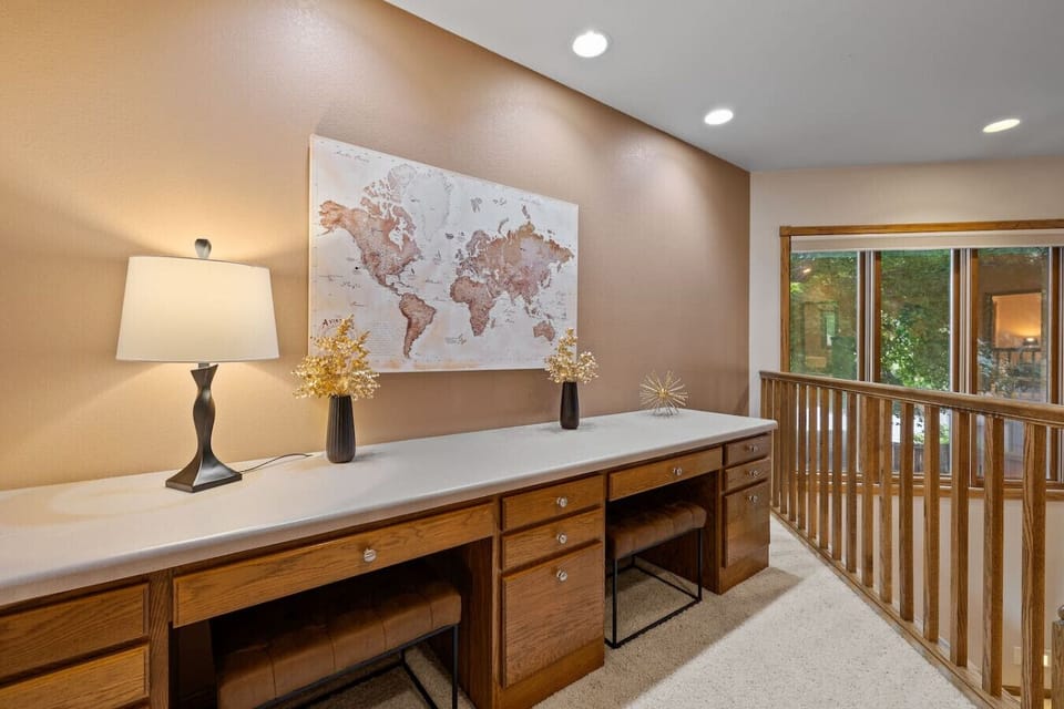 A stylish cabinet with a lamp on top, chairs neatly tucked underneath, and a large world map frame as the focal point.