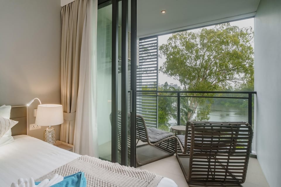 Master bedroom with direct access to private balcony equipped with outdoor furniture and tropical views