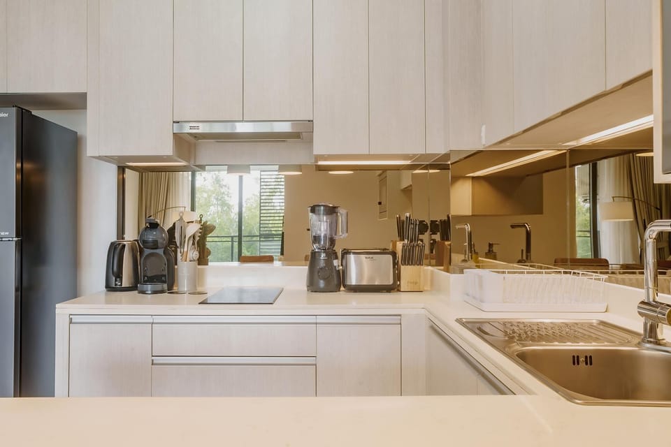 Bright open-plan kitchen featuring hob, microwave, fridge, kettle, toaster, and full cooking utensils.