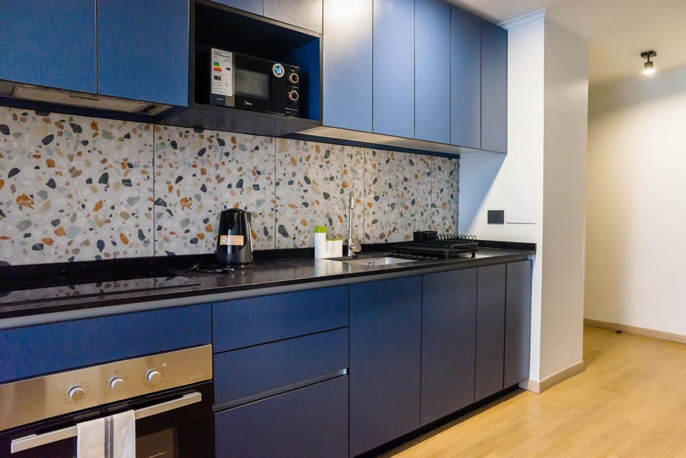 Modern kitchen with terrazzo backsplash and sleek blue cabinets, ideal for culinary creativity.