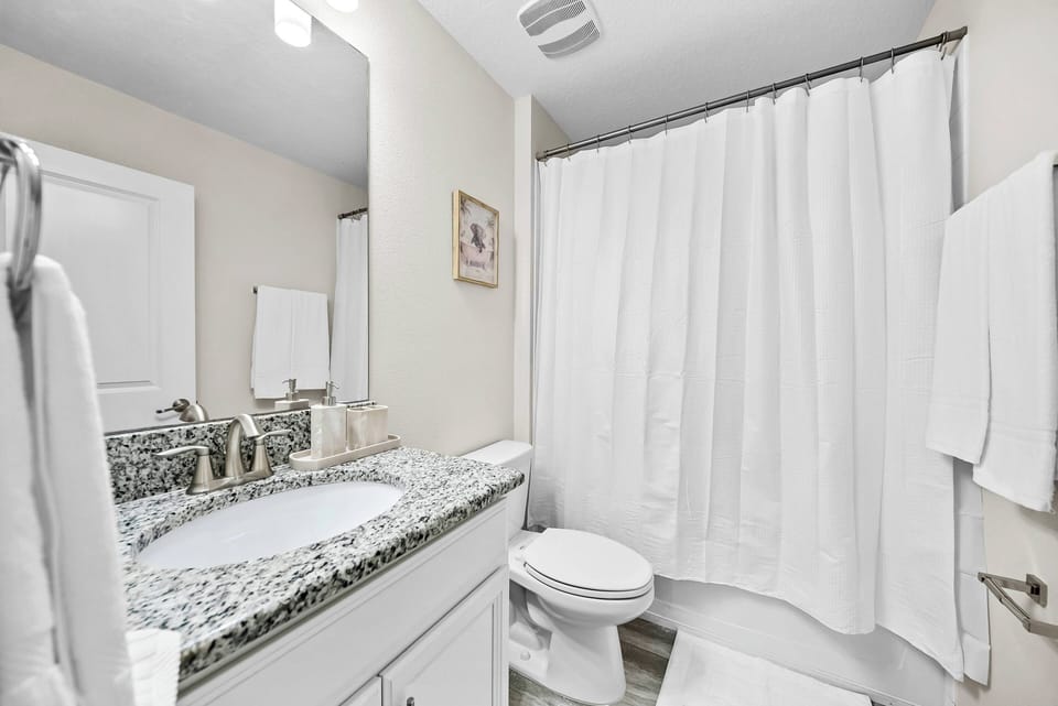 Step into this well-appointed bathroom, featuring a sleek granite countertop and a clean, crisp design. Soft white towels and a calming color palette create a refreshing atmosphere, perfect for unwinding after a day of adventure.