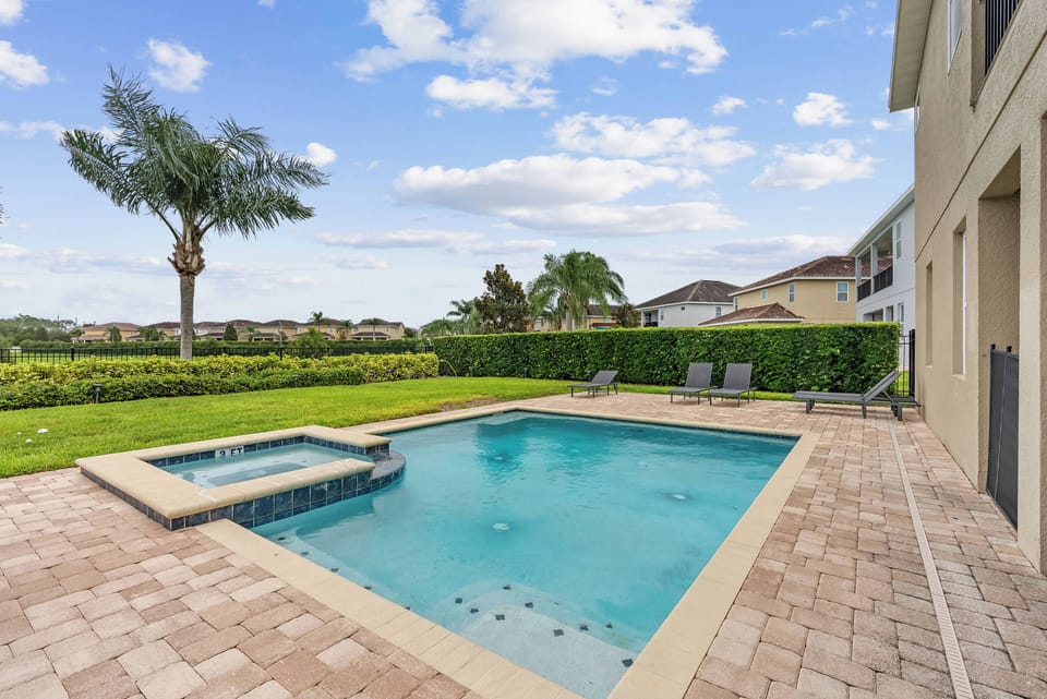 Step outside to enjoy your own private oasis featuring a sparkling blue pool framed by elegant pavers. The inviting hot tub glistens under the sun, surrounded by lush greenery that provides a sense of tranquility and privacy.