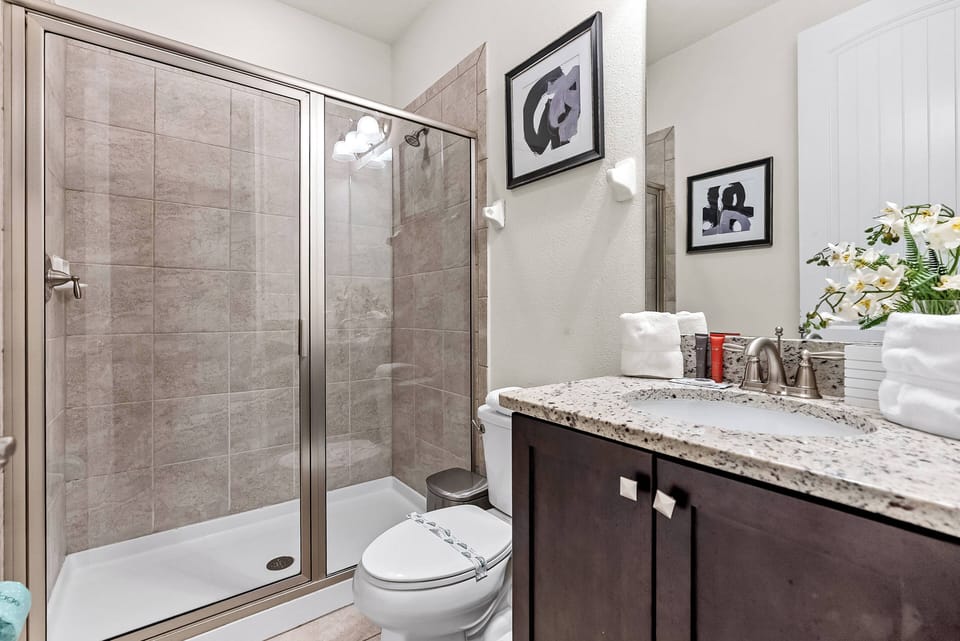This elegant bathroom boasts a sleek glass shower and stylish granite countertop, enhanced by modern fixtures. Its neutral tones create a calming atmosphere, making it the perfect place for relaxation.