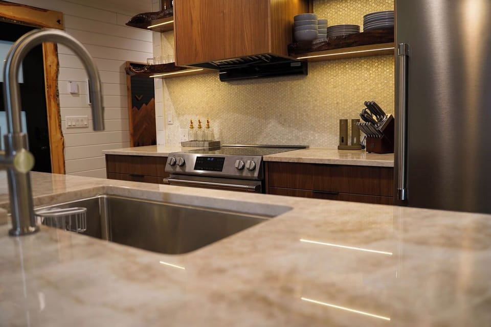 Walnut cabinetry, live-edge shelving, and natural textures bring warmth and character to the modern kitchen.