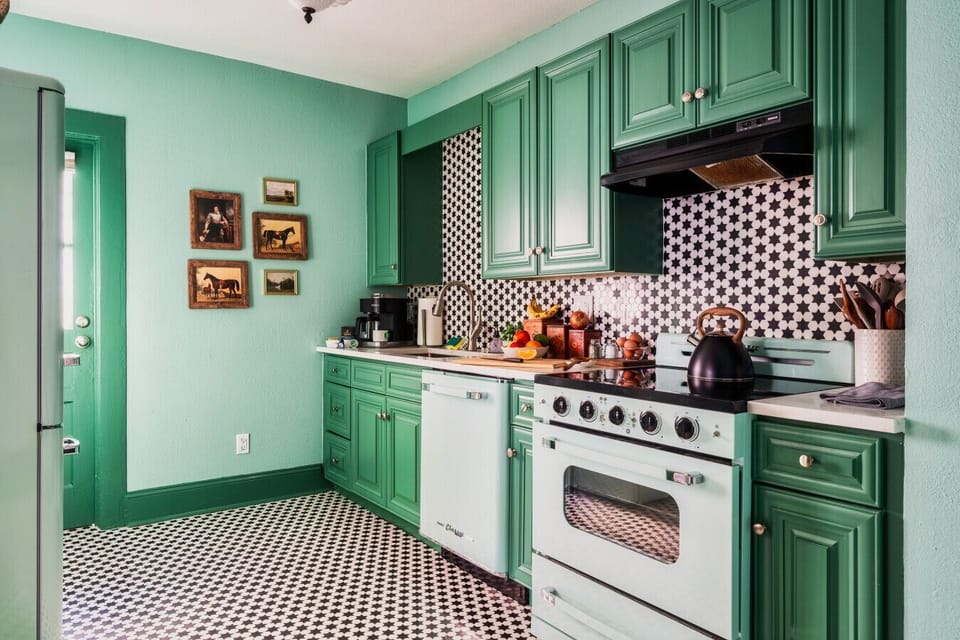 Step into a retro-inspired kitchen with vibrant green cabinetry, a charming vintage-style oven, and striking black-and-white star-patterned tile flooring